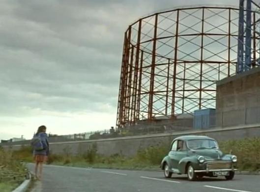 A scene in the English midlands from the film "Felicia's Journey", showing two main characters in front of an old gasworks with a Morris Minor car